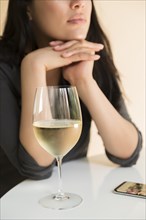 Woman at table by smart phone and glass of wine