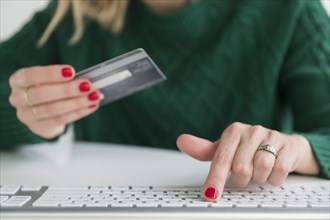 Woman holding credit card and typing on keyboard