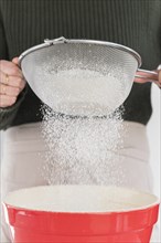 Woman sifting flour into bowl