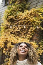 Smiling woman looking up against autumn bush