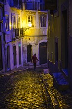 Woman walking in alley at night in Lisbon, Portugal