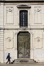 Woman walking past old building in Lisbon, Portugal