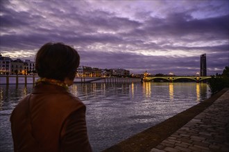 Woman by Guadalquivir river at sunset in Seville, Spain