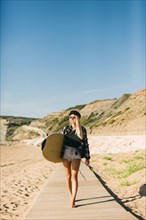 Woman holding surfboard on boardwalk