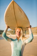 Woman holding surfboard above her head at beach