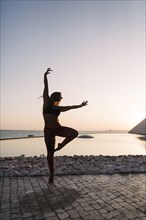Silhouette of woman dancing at sunset