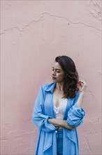 Smiling woman wearing blue by pink wall