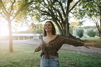 Smiling woman with her arms outstretched in park
