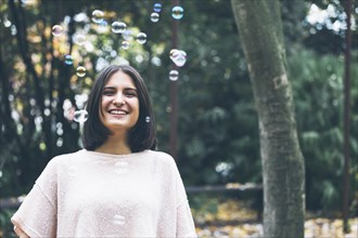 Smiling teenage girl under bubbles