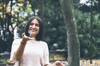 Smiling teenage girl playing with bubbles