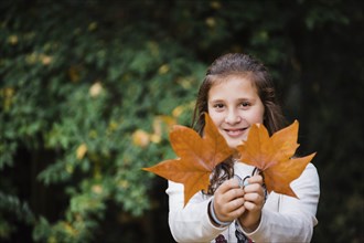 Smiling girl holding autumn leaves
