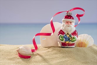 Santa decoration and shells on sand