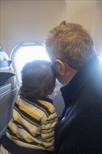 Man and child looking out airplane window