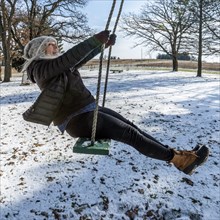 Smiling woman on swing in snow