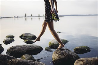 Barefoot woman stepping on rocks in sea