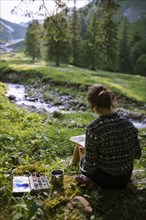 Woman painting with watercolors by river in Appenzell, Switzerland