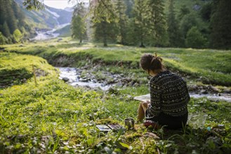 Woman painting with watercolors by river in Appenzell, Switzerland