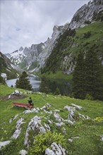 Woman sitting on bench by mountains in Appenzell, Switzerland