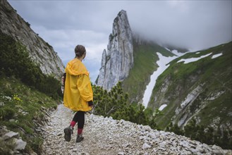 Woman wearing yellow jacket by mountains in Appenzell, Switzerland