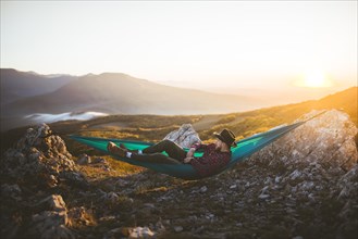 Man lying on hammock in mountain range