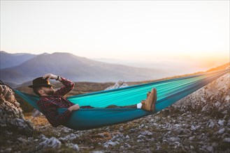 Man sleeping on hammock in mountain range