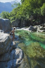 Woman wearing bikini on rock by river