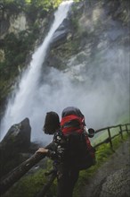 Woman wearing backpack by waterfall