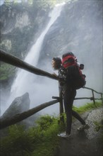 Woman wearing backpack by waterfall