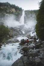 Woman on rocks by waterfall