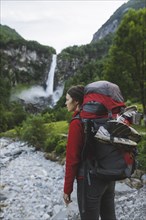 Woman wearing backpack with waterfall in distance