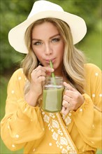 Young woman drinking smoothie from mason jar