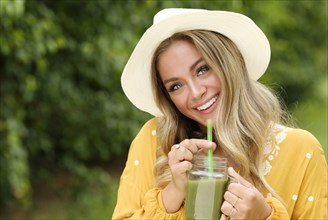 Smiling young woman with smoothie in mason jar