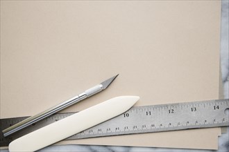 Knife, paper scorer, and ruler on paper
