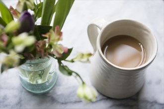 Cup of coffee beside flowers in vase