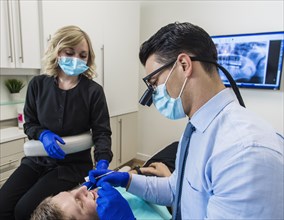 Dentist and dental nurse examining patient's teeth