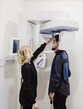 Dental nurse adjusting x-ray machine for patient