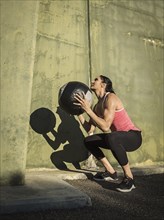 Woman squatting with medicine ball