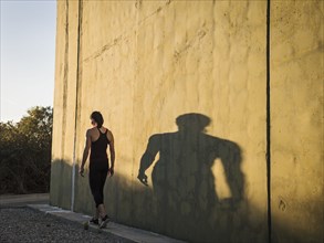 Woman in sportswear walking by concrete wall