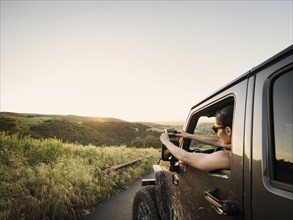 Woman in off road vehicle photographing sunset