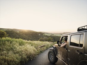 Woman in off road vehicle looking at sunset