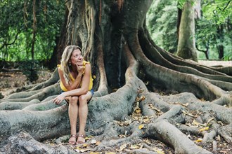 Woman sitting on roots of tree