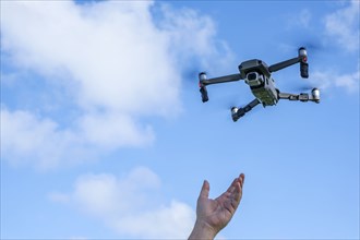 Hand reaching for flying drone