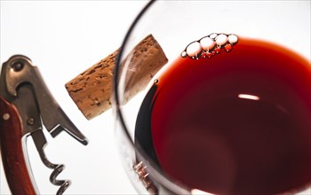 Glass of red wine with corkscrew and cork