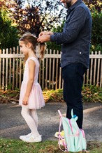 Man tying his daughter's hair in ponytail
