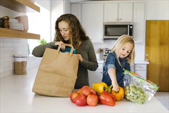 Mother and daughter unpacking groceries