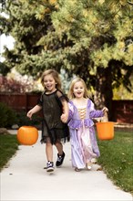 Girls in Halloween costumes running on path