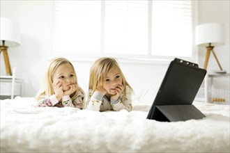 Girls watching movie on digital tablet while lying on bed