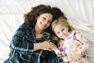 High angle view of mother and daughter in pajamas lying on bed