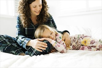 Mother and daughter hugging on bed