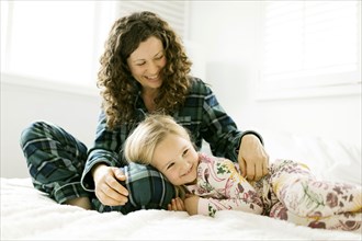 Mother and daughter hugging on bed